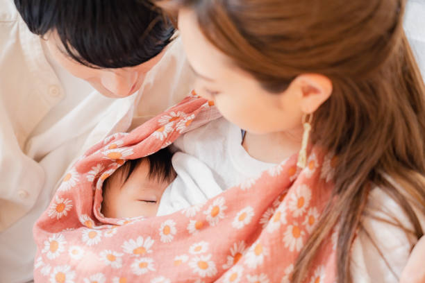 madre che allatta al seno il suo bambino con il padre - sucking asian ethnicity baby mother foto e immagini stock