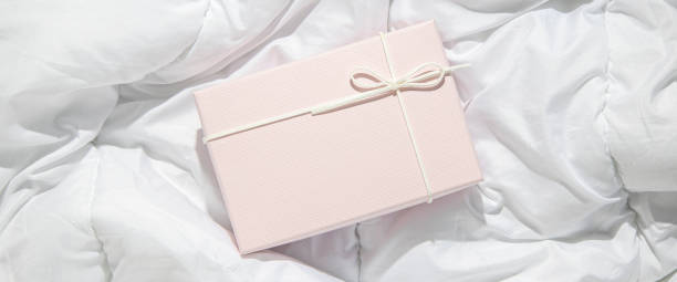 istock Light pink gift box on crumpled white fabric. Top view, flat lay. Banner 1445907637