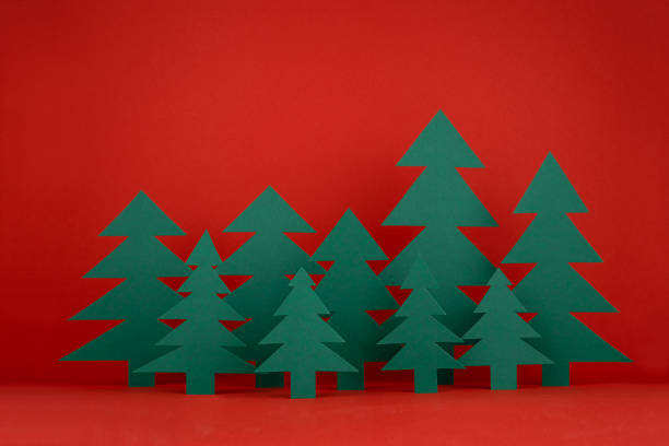 istock Bright Christmas background with paper green spruce forest on red backdrop in minimalist modern style. New year scene for presentation products and advertising text, card, poster, flyer. 1445910678