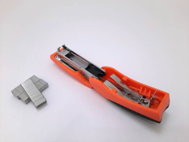 istock Orange paper stapler and staples on white background 1445912955