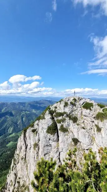 A vertical panoramic of the Hochlantsch mountain peak with a cross on top of it