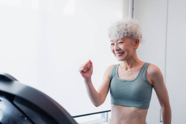 ジムでランニングマシンに乗る年配の女性 - treadmill gym health club exercising ストックフォトと画像