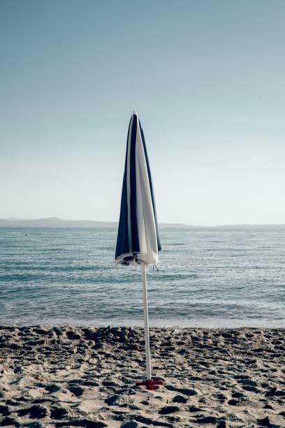 istock Closed umbrella standing at a sandy beach on a sunny morning 1445919201