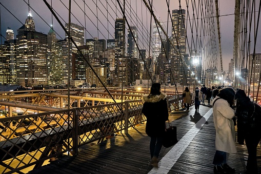 Some people walking on the Brooklyn Bridge in the nighttime. New York.