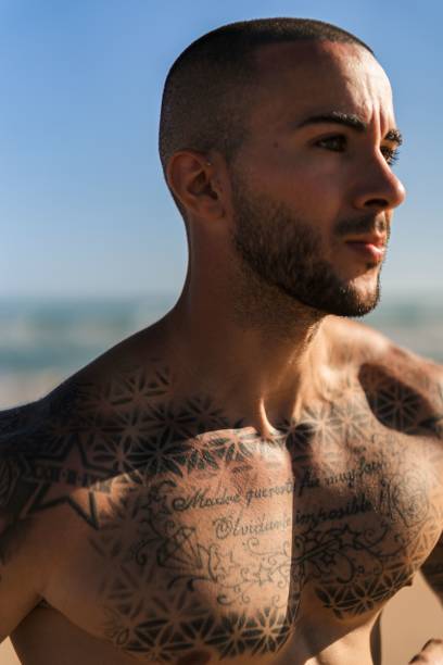 istock An attractive topless man with tattoos running on a beach next to a sea 1445919971