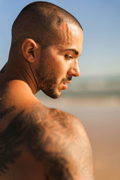 istock An attractive topless man with tattoos standing on a beach next to a sea 1445919973