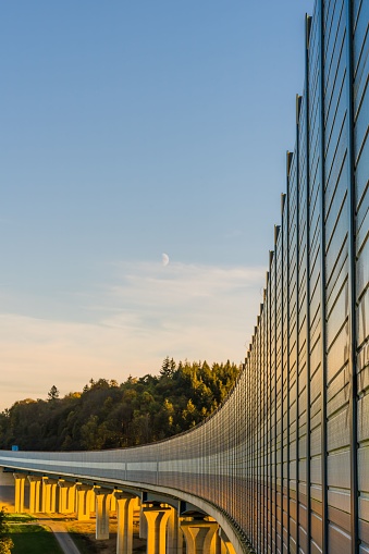 A noise barrier on a45 bridge illuminated by sun rays, surrounded by trees in Wetzlar, Germany