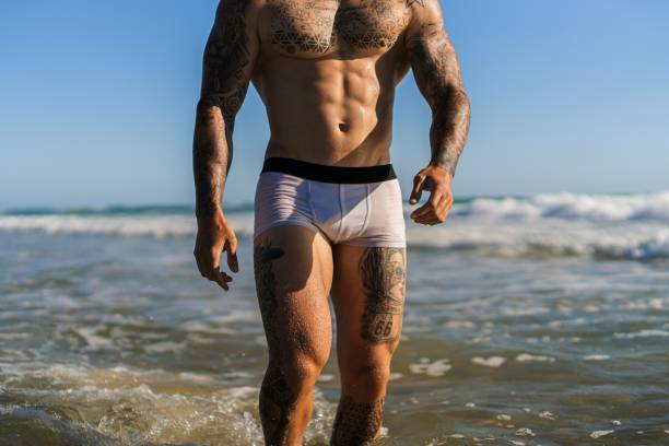 istock Attractive fit tattooed guy at a sandy beach on a beautiful summer day 1445921236