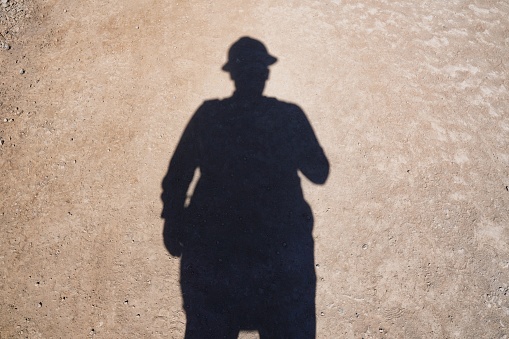 A shadow of a man on the ground in an engineering hat