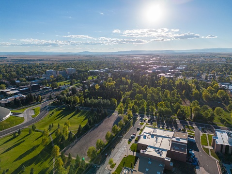 A drone shot of Laramie Wyoming neighborhood's cityscape with greenery, sunlight and cloudy sky