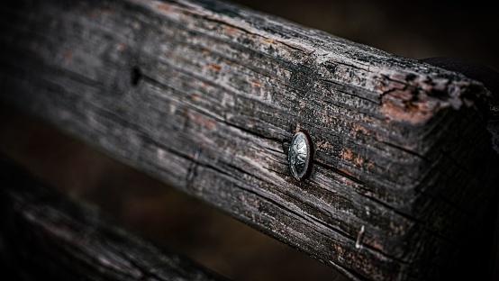 A closeup of an old wooden bench with a nail isolated on a blurred background