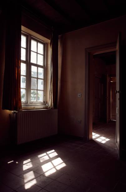 istock Vertical low-angle of an empty room with a sunlit old window 1445927081
