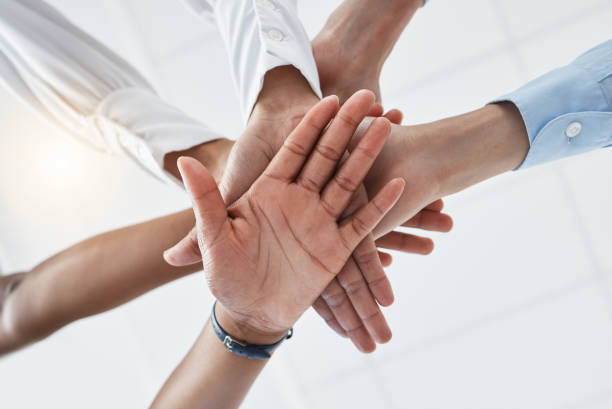 istock Hands, collaboration and motivation with a team in business standing in a huddle or circle from below. Teamwork, success and unity with an employee group working together with a goal or vision 1445927270