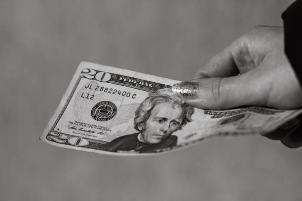 istock Grayscale closeup of a hand holding USD banknotes - perfect for background 1445928701