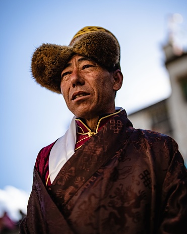 Lo Manthang, Nepal – May 28, 2022: A vertical portrait of a Tibetan Buddhist village elder in traditional clothes at the Tiji Festival in Lo Manthang