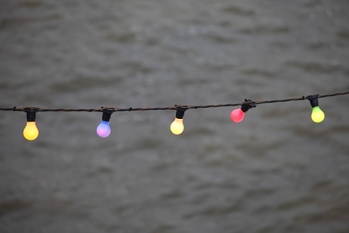 A wire with colorful light bulbs glowing on a blurry brown background