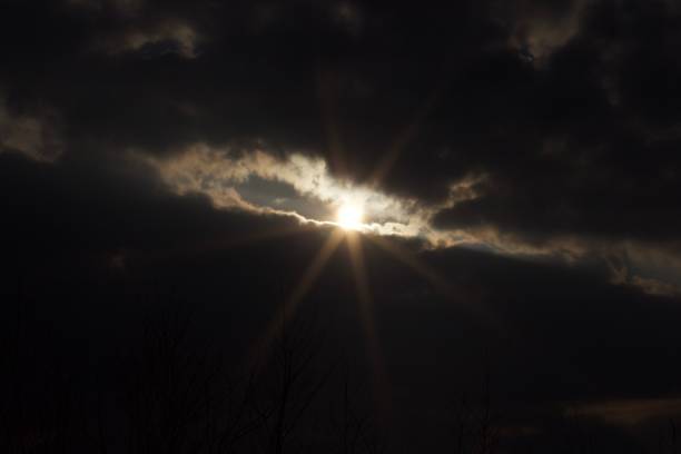 A view of the sun shining through dark clouds