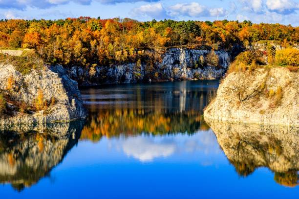 istock Gorgeous landscape with a calm lake reflecting cliffs and vibrant autumnal trees under a cloudy sky 1445933012