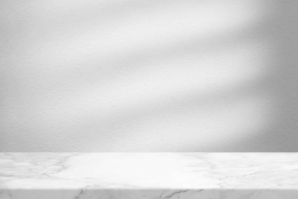 istock Marble Table with White Concrete Wall Texture Background with Light Beam and Shadow, Suitable for Product Presentation Backdrop, Display, and Mock up. 1445933137