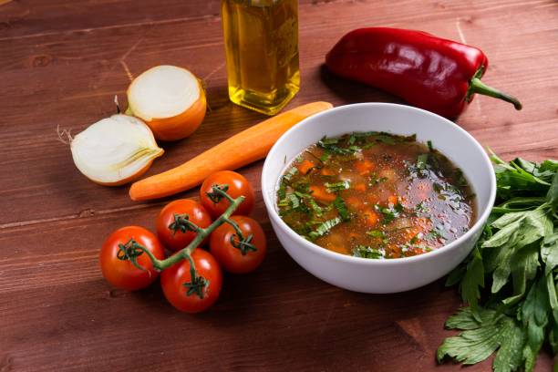 istock Warm red soup served in a white bowl surrounded by fresh vegetables 1445934913
