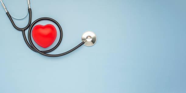 uno stetoscopio e un cuore rosso su uno sfondo azzurro - heart health foto e immagini stock