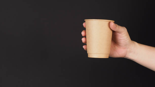istock Hand hold paper coffee cup on black background. 1445935779