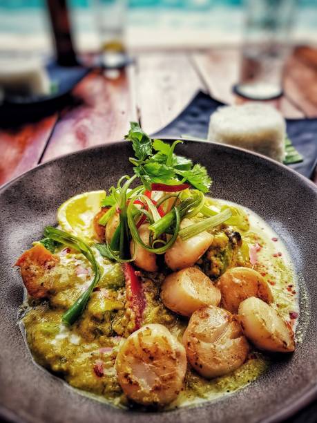 Vertical shot of pan-seared scallops with sauce and vegetable garnish