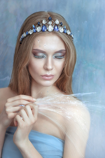 beautiful girl in a crown of stones. With New Year's decorations. On a blue background. Portrait