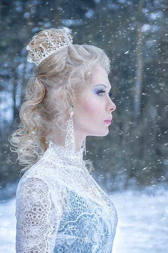 Beautiful young woman in fairy tale forest with long luxurious dress