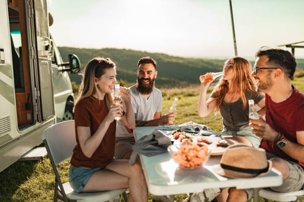 istock Young cheerful couples talking at picnic table by the camp trailer. 1445938956
