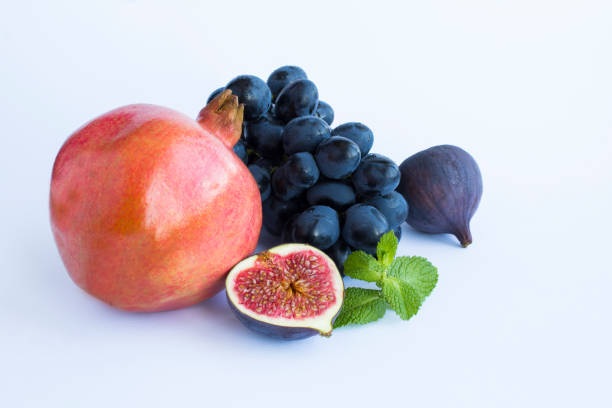 Pomegranate, blue figs and grape on the white background. Copy space. Close-up.