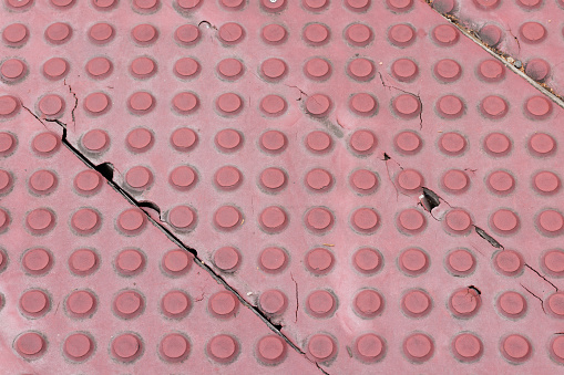 Pattern of studs and lines on a rubber mat to prevent slipping on a sidewalk.