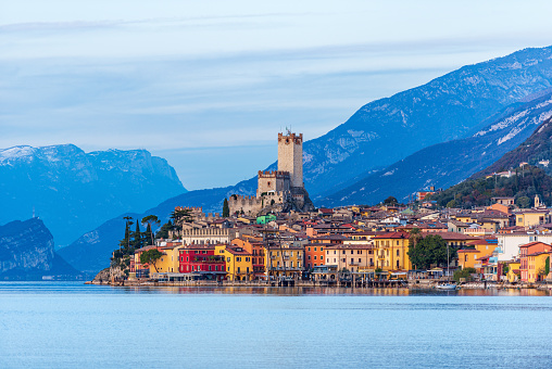 Lake Garda (Lago di Garda) and the small Malcesine village with the castle at sunset. Verona province, Italy, Veneto, southern Europe. On background the coast of the Lombardy and Trentino-Alto Adige.