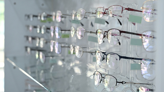 Fashionable corrective eye glasses on a shelf in optical store. Optics, health care and vision concept.