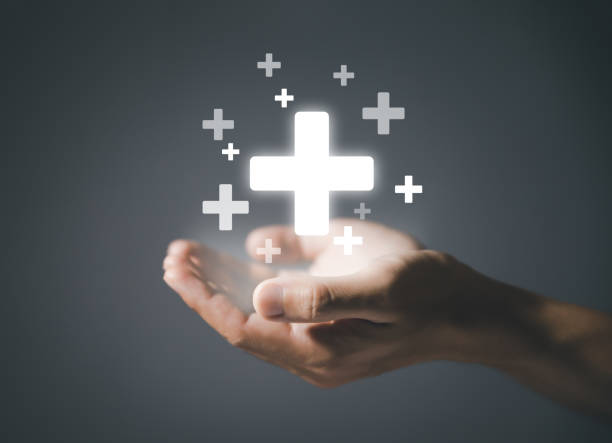 istock Both hands showing a medical plus sign on a dark background 1445946360
