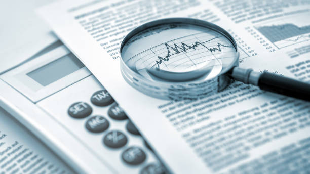 Magnifying glass, calculator and charts on paper