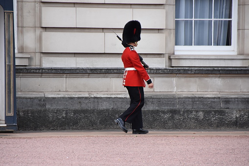 London, England 08 13 2016 A member of King's Guard at Buckingham Palace in London. He is side view, marching along. He is responsible for the protection of the sovereign residence.