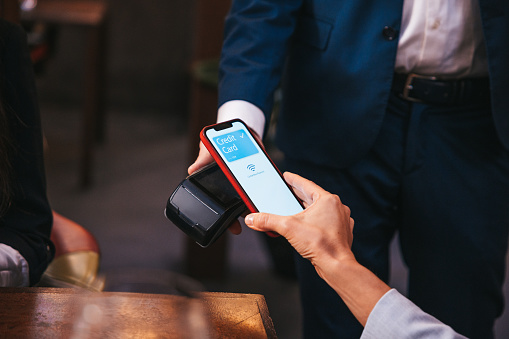 Business people paying the restaurant check using mobile contactless payments.