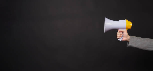 istock Hand is hold megaphone and wear grey suit on black background. 1445951196
