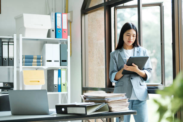 istock Young asian businesswoman working at office using laptop. 1445954290