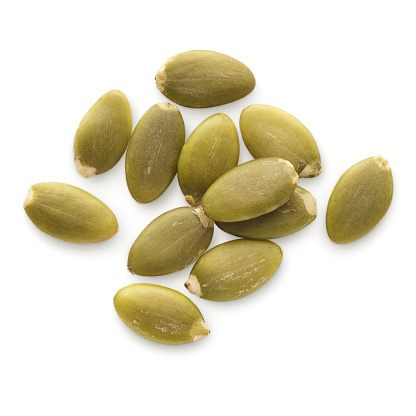 Food ingredients: small heap of dried peeled pumpkin seeds, isolated on white background