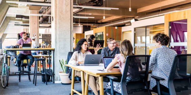 emprendedores teniendo una reunión en la oficina - oficina de plan abierto fotografías e imágenes de stock