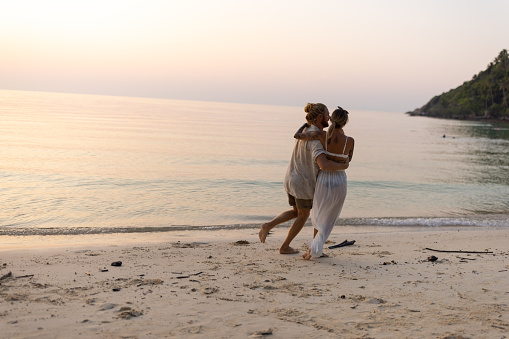 Carefree Caucasian couple dancing on the beach during sunset