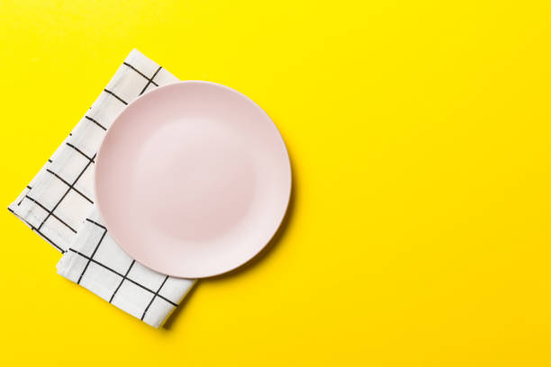 istock Top view on colored background empty round pink plate on tablecloth for food. Empty dish on napkin with space for your design 1445970253