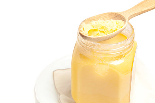 istock Ghee in jar and wooden spoon isolated on white background 1445970896