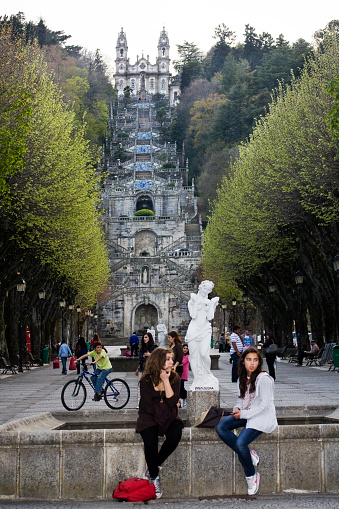 Lamego, Portugal- April 1, 2011: Two young women sitting at the bottom of the monumental staircase of Nossa Senhora dos Remedios sanctuary church, Lamego, Viseu district, Portugal. Town square , city life.