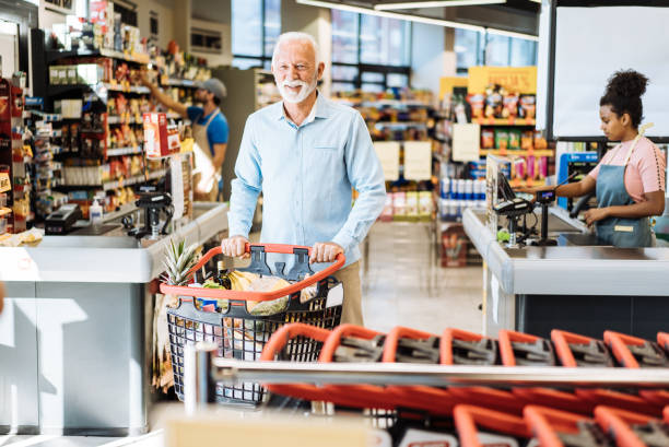 istock Retired man buying groceries, looking at camera with full shopping bag 1445978342