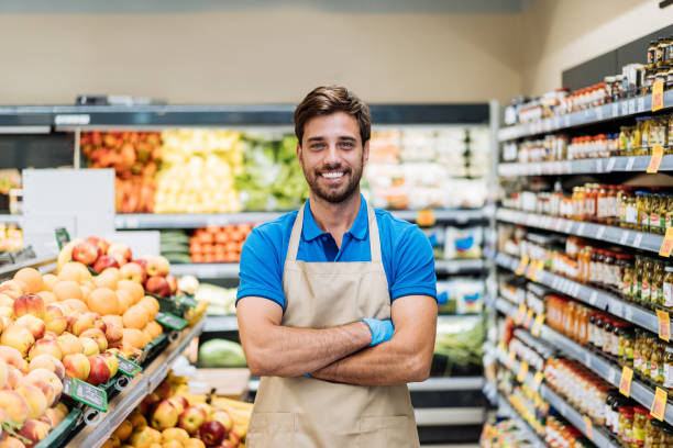 istock Employee in supermarket arranging fresh fruit and looking at camera 1445978894