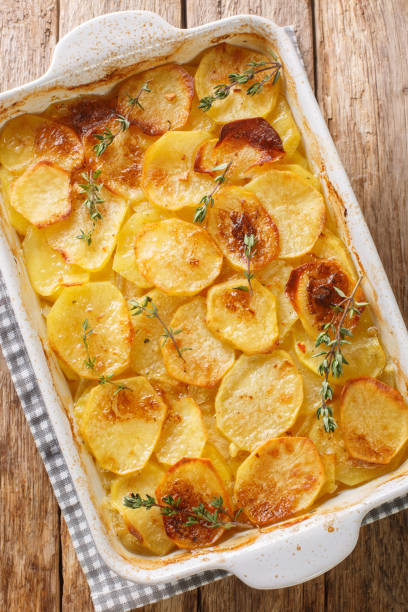 istock appetizing gratin baked potato with herbs, onion and garlic in a ceramic baking dish closeup. Vertical top view 1445981885