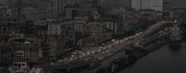 War in Ukraine.  View of Kyiv from the observation deck in the evening during a blackout. Dark houses and unlit streets are visible, and the lights of passing cars are visible.